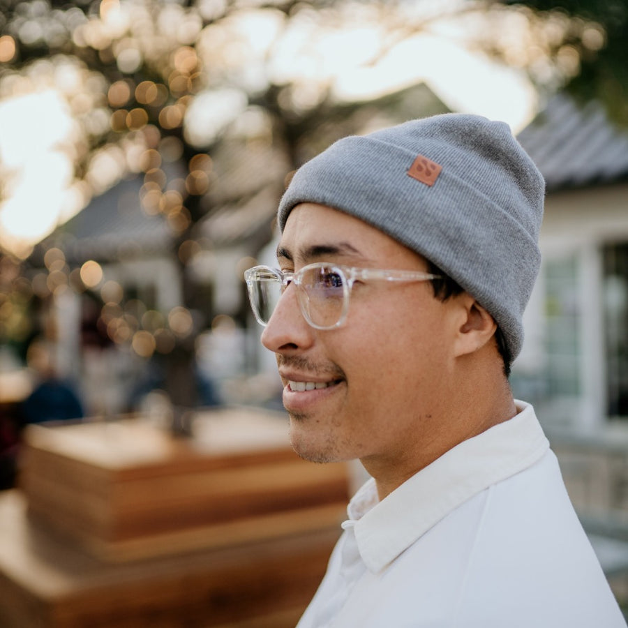 Man wearing a gray beanie with a leather patch, smiling outdoors, showcasing the SafeSleeve RF Blocking Beanie.