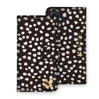 Detachable SafeSleeve phone case with black and white polka dot design for iPhone 16 series, featuring a fold-over cover and logo.