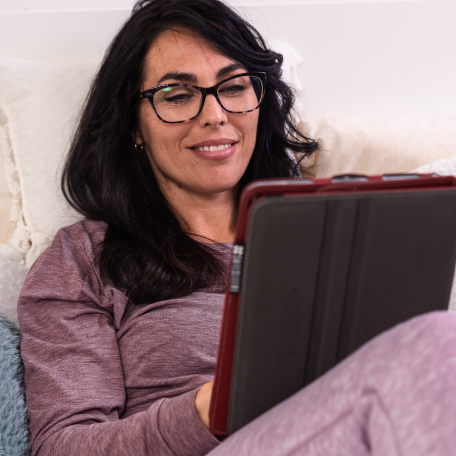 Woman using an iPad with a blue light blocking screen protector for iPad 10.2, 8th and 9th generation, while relaxing on a couch.