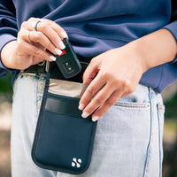 Person placing a key fob into a black security and privacy pouch attached to their jeans pocket.